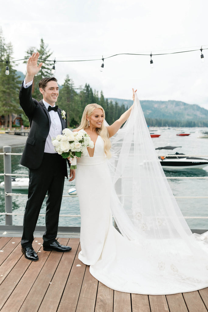 Wedding couple waving from a dock in Lake Tahoe